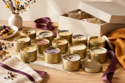 Lot de petites bougies parfumées en pots métalliques présenté dans un décor chaleureux sur bois clair