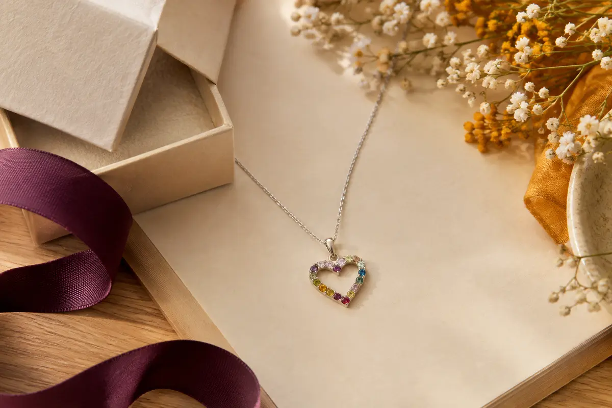 Collier en argent 925 avec pendentif cœur personnalisé et pierres de naissance, présenté sur un fond crème.