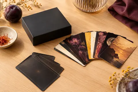 Boîte noire et cartes d’un jeu d’ambiance adulte disposées sur une table en bois clair.