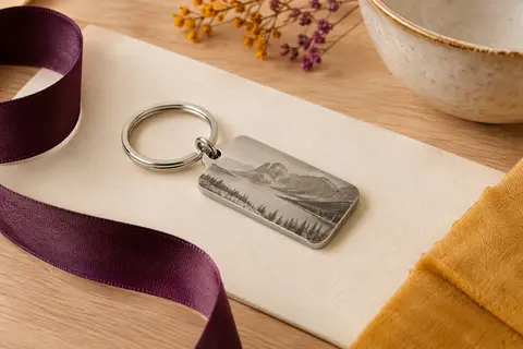 Porte-clés en acier inoxydable avec gravure personnalisée, présenté sur un fond crème et bois clair