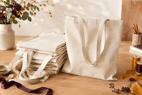 Lot de dix tote bags vierges en coton naturel à longues anses, présenté sur un fond clair.