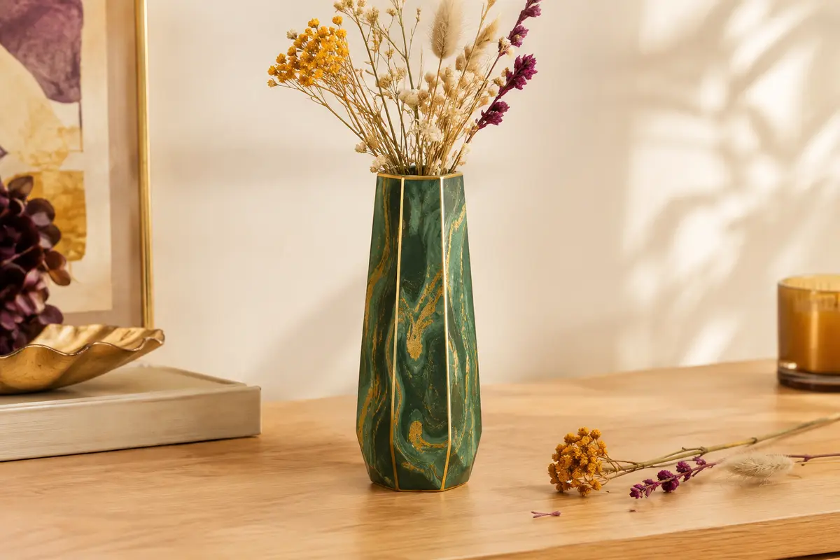 Vase hexagonal en céramique vert et doré à motif marbré, posé sur une console en bois clair.