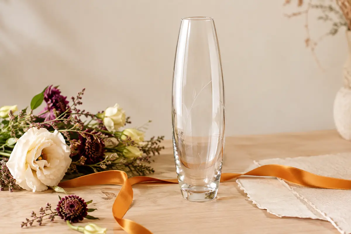 Vase ovale en verre transparent personnalisé, posé sur une table en bois clair avec quelques fleurs
