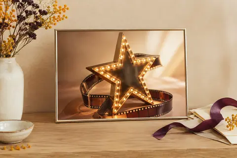 Affiche encadrée avec étoile décorative inspirée du cinéma, posée sur un meuble en bois clair.