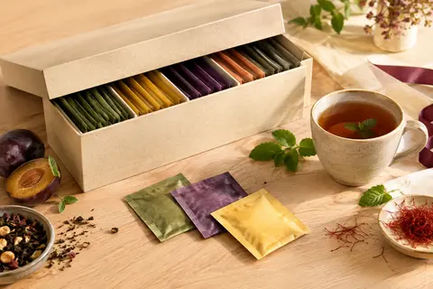 Coffret Pukka de thés et infusions bio présenté avec quelques sachets sur un fond de bois clair.