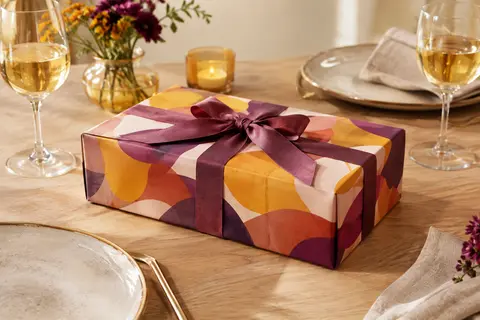 Coffret cadeau rectangulaire multicolore posé sur une table dressée pour un repas à deux